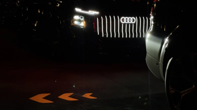 a photo of the projected turn signal in front of a Q9 with its headlights and grille illuminated at night time