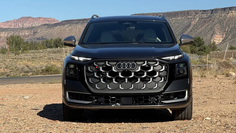 head-on shot of the gray SQ9 parked on dirt in front of a blue sky and a shrubby mountain range