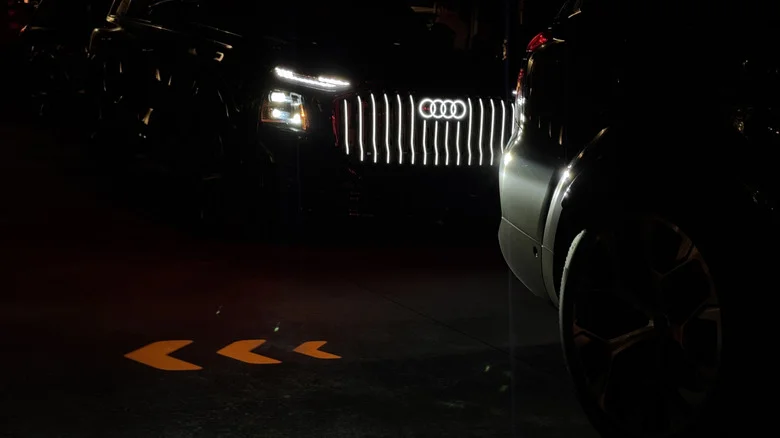 Photo of a Q9's illuminated grille behind another Q9 showing its orange arrow turn signal projector