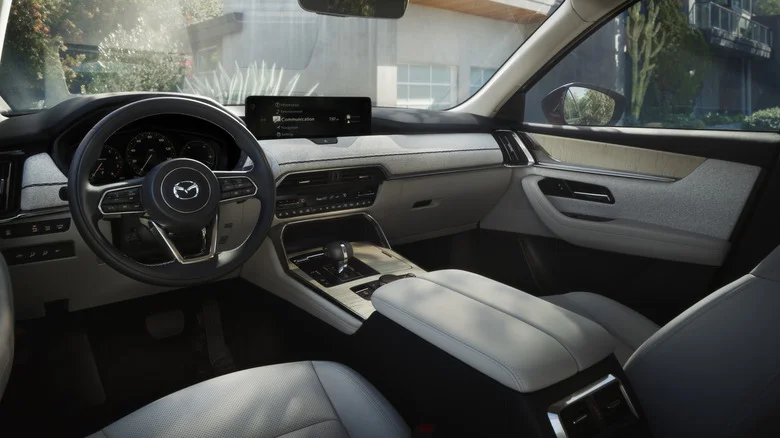 The white dashboard in a CX-90 with plants and a building visible out the windows