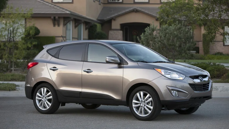 A brown 2011 Hyundai Tucson in front of a house.
